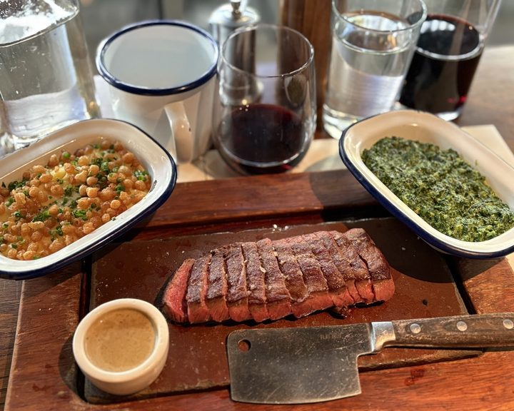 Sliced steak with sauces and sides at Flat Iron Southbank