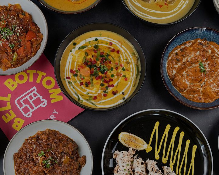 Overhead spread of Indian curries and grilled dishes at Bell Bottom Eatery