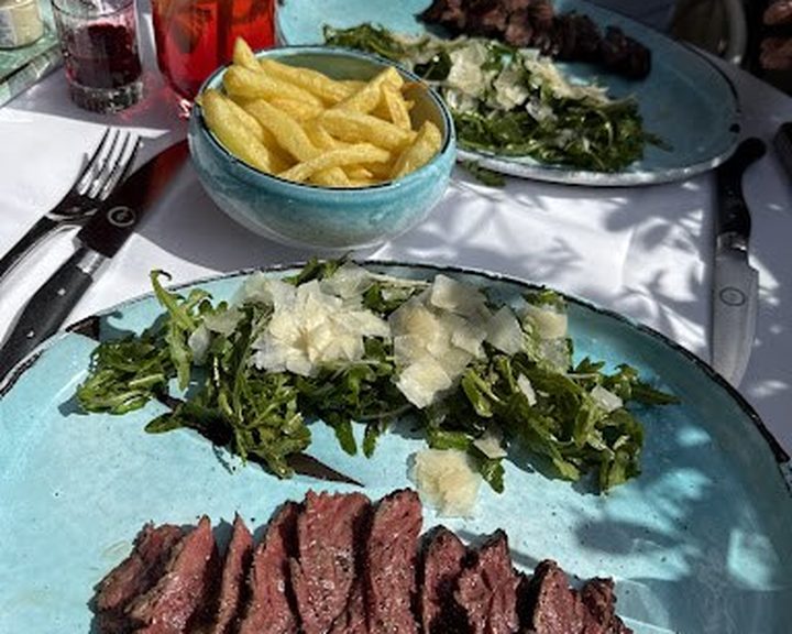 Sliced steak with fries and dressed greens at La Mome London