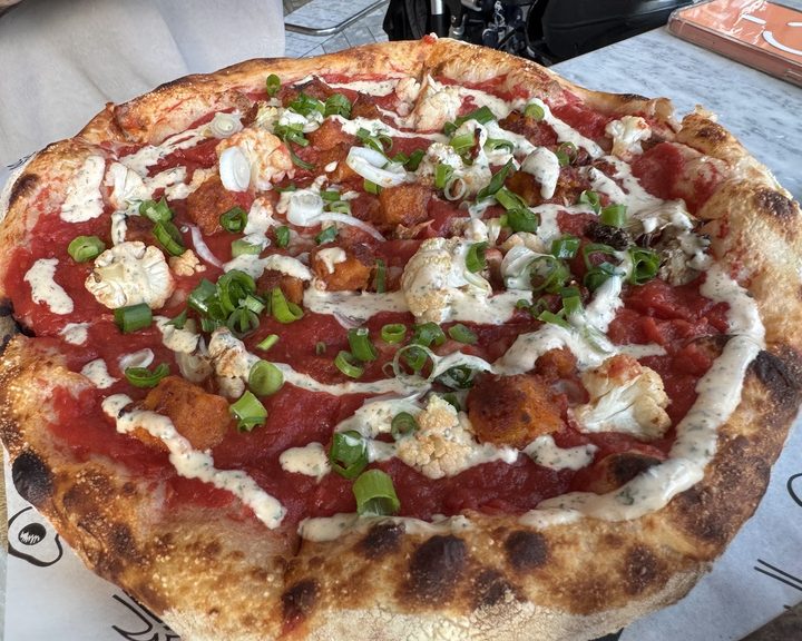A wood-fired pizza topped with tomatoes and cheese at Bondi Green