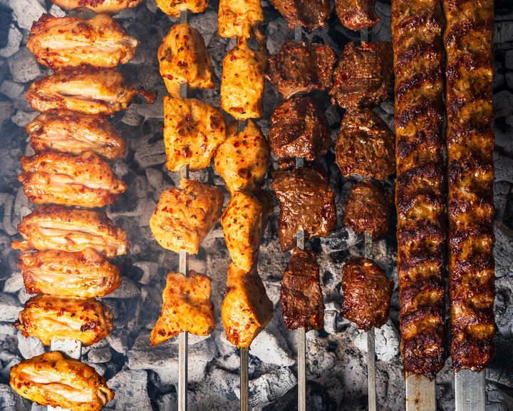 Lamb and chicken skewers cooking over charcoal at E-Mono