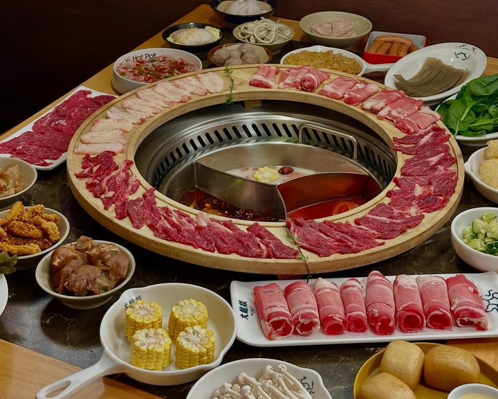 Hot-pot broths surrounded by sliced beef, vegetables and mushrooms at Da Long Yi