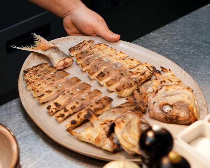 Whole butterflied fish grilled and served on a platter at Kima