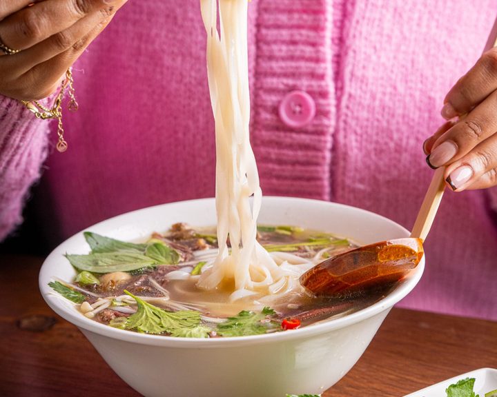 A bowl of Pho noodle soup with noodles lifted above the broth